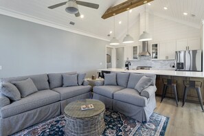 Een moderne woonkamer met een hoekbank, een ronde salontafel en een vloerkleed met een patroon.