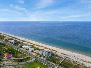 An aerial view of a coastal area with a road, beachfront properties, and a clear view of the ocean. - Oak Rest Barn, is a custom built gulf front home w/pool, pet friendly, $250 cred (Port Saint Joe)