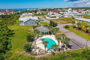 Ett flygbildsbild av ett bostadsområde med hus, en swimmingpool och utsikt över havet.