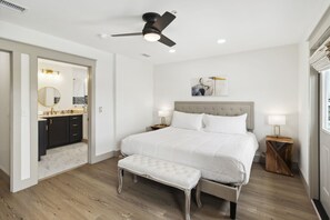 Ein Schlafzimmer mit einem Bett, einer Bank, einem Deckenventilator und einem Nachttisch mit Lampe.