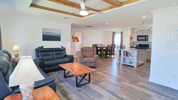 A modern living room with a sofa, armchair, and coffee table, a dining area with chairs, and a kitchen with appliances. - PETE'S PARADISE IS MODERN, SPACIOUS FLOOR PLAN! GREAT FENCED IN BACKYARD WITH FI (Port Saint Joe)