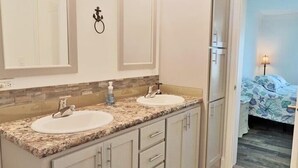 A bathroom with two sinks, vanity cabinets, and a mirror with lights. - PETE'S PARADISE IS MODERN, SPACIOUS FLOOR PLAN! GREAT FENCED IN BACKYARD WITH FI (Port Saint Joe)