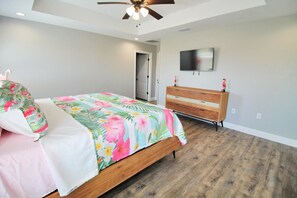 A bedroom with a bed, a wooden dresser, a ceiling fan, and a television on the wall. - PINK FLAMINGO, 3BD/2BA W/FENCED IN BACKYARD IN QUIET NEIGHBORHOOD! COMMUNITY POO (Mexico Beach)
