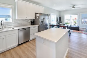 A modern kitchen with white cabinetry, a dishwasher, and a central island. - PURPLE HAZE IS 200 STEPS TO THE BEACH! 2BD/3BA W/BONUS BUNK ROOM! (Mexico Beach)