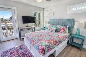A bedroom with a bed, a TV, a desk, and a view of the outside. - PURPLE HAZE IS 200 STEPS TO THE BEACH! 2BD/3BA W/BONUS BUNK ROOM! (Mexico Beach)