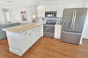 A modern kitchen with white cabinets, stainless steel appliances, and a granite countertop. - RAY'S ROOST WITH 6BD, 2 FULL KITCHENS, 2 LIVING AREAS, PERFECT FOR MULTI FAMILIE (Mexico Beach)