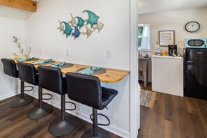A kitchen with a wooden island, bar stools, a clock, and a refrigerator. - "Recuperation Cottage" offers gulf views and is steps to the beach! Pet-friendly (Port Saint Joe)