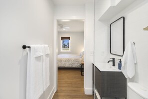 Ein modernes Badezimmer mit einem weißen Waschbecken, einer dunklen Arbeitsplatte und einem Spiegel.