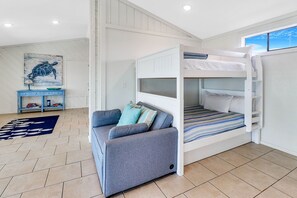 Une pièce avec un lit superposé, un canapé, une petite table et un tableau accroché au mur.