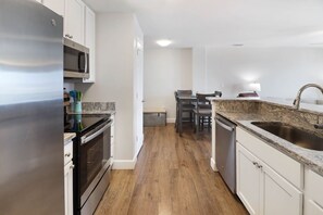 A modern kitchen with stainless steel appliances, a granite countertop, and a dining area with a table and chairs. - "Sandals and Sunsets" located in a gulf front community! Steps to paradise! Pet (Mexico Beach)