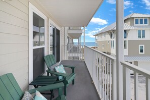 A balcony with two green Adirondack chairs and a bench, overlooking a beach and other buildings. - "Sandals and Sunsets" located in a gulf front community! Steps to paradise! Pet (Mexico Beach)