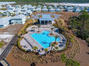 En vy från ovan av ett semesterområde med en central pool omgiven av avslappningsområden och palmer.