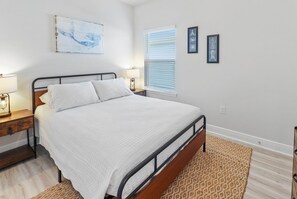 Een slaapkamer met een bed, nachtlampjes, een vloerkleed en wanddecoratie.