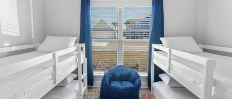 A room with two bunk beds, a blue bean bag chair, and a patterned rug.