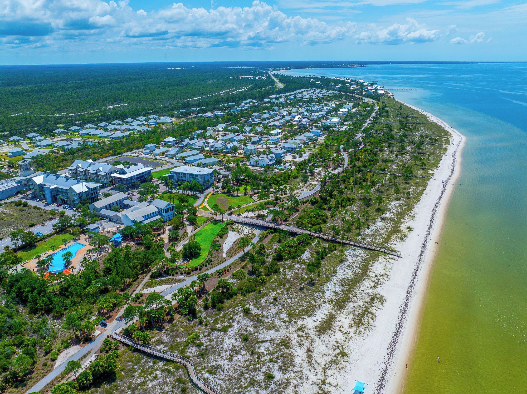 An aerial view of a coastal resort with multiple buildings, a beach, and a waterway.