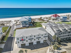 Ein Küstenhotel mit mehreren Gebäuden, ein Strand im Hintergrund und ein klarer Himmel.