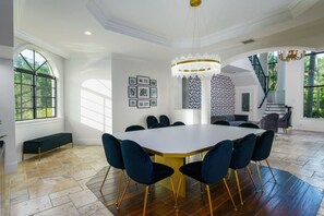 A spacious dining area with a large round table, dark upholstered chairs, and a chandelier. - Luxury Mansion | 7K SF | Pool & Game Room (Plantation)