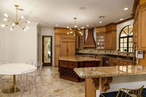 A spacious kitchen with granite countertops, wooden cabinets, and a central island. - Luxury Mansion | 7K SF | Pool & Game Room (Plantation)