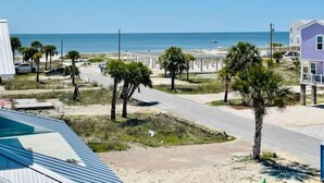 Ein Küsteneigentum mit einer Straße, die zum Strand führt, Palmen und freiem Blick auf das Meer.
