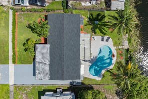 Una propiedad residencial con piscina, un patio cubierto y una casa grande con techo inclinado.