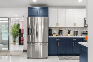 Una cocina moderna con electrodomésticos de acero inoxidable, armarios azul oscuro y salpicadero de azulejos.