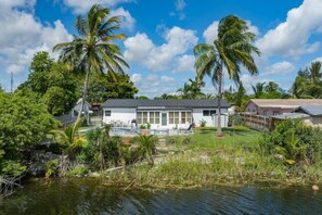 A house with a pool, surrounded by palm trees and vegetation. - 3‑BR Retreat w Pool near the Beach - Car charger (Pompano Beach)