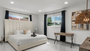 Un dormitorio moderno con una cama grande, una mesita de noche, una lámpara colgante y vistas al exterior.