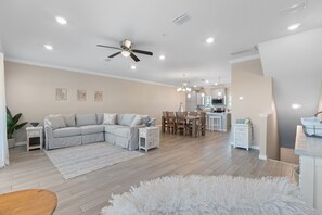 Een moderne woonkamer met een modulaire bank, een eethoek en een keuken met witte kasten.