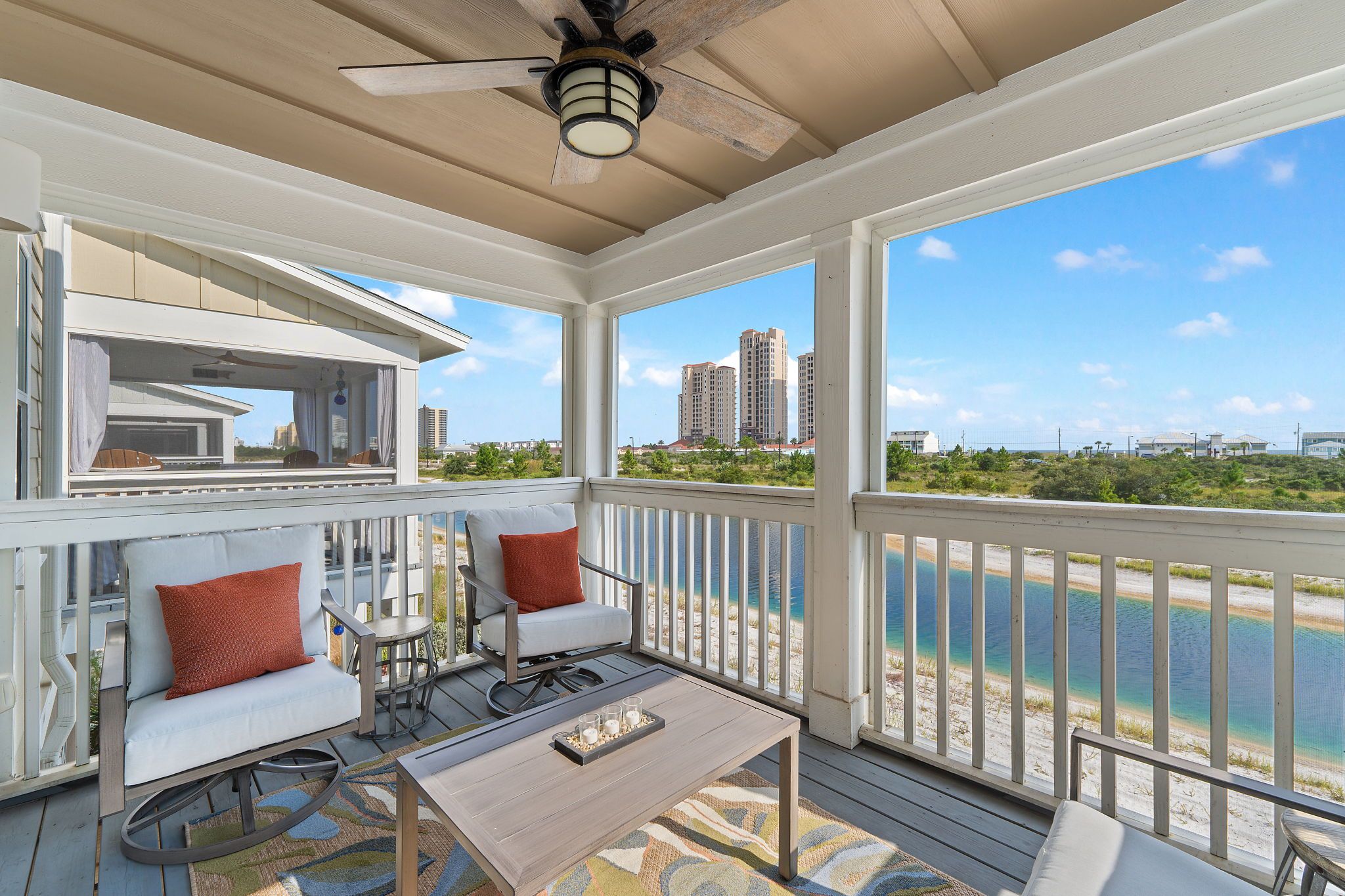 A covered outdoor seating area with a view of the water and buildings in the distance.