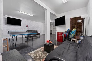 Ein Zimmer mit einem Pingpongtisch, einer Couch, einem Fernseher und einem Fahrrad.