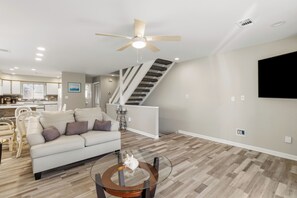 Ein modernes Wohnzimmer mit einer Couch, einem Couchtisch und einer Treppe, die in einen oberen Bereich führt.