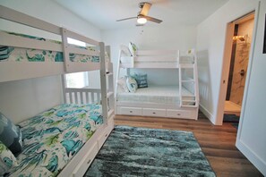A bunk bed room with a ceiling fan, a small window, and a door leading to a bathroom. - SHORE BEATS WORK IS 500 STEPS TO BEACH! MODERN, IMMACULATE TOWNHOME! (Mexico Beach)