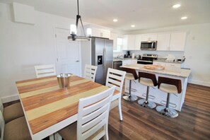 A modern kitchen with white cabinets, a stainless steel refrigerator, a microwave, and a granite countertop. - SHORE BEATS WORK IS 500 STEPS TO BEACH! MODERN, IMMACULATE TOWNHOME! (Mexico Beach)