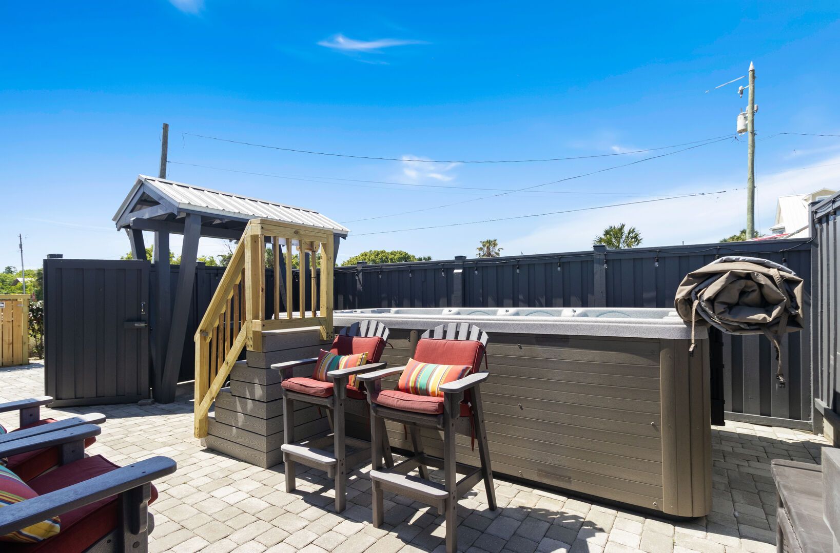 A patio area with two Adirondack chairs, a wooden playhouse, and a hot tub.