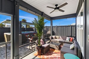 Eine überdachte Terrasse mit Sitzgelegenheiten, einem Deckenventilator und Blick auf einen Hinterhof-Grillbereich.