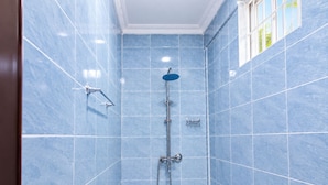 Un baño con paredes de azulejos azules, un cabezal de ducha y un accesorio de ducha manual.