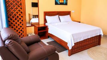 A bedroom with a wooden bed, a brown leather chair, a bedside table, and a wall-mounted TV.