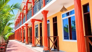 Un edificio con varios balcones, columnas rojas y un paseo cubierto de baldosas.