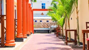 Un camino que lleva a un edificio con columnas rojas, una cebra y palmeras.