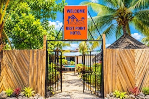 A wooden gate leading to a hotel entrance with a sign reading 'WELCOME BEST POINT HOTEL'.