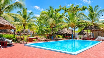 A swimming pool with lounge chairs and palm trees.