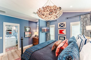 A bedroom with a bed, a dresser, a nightstand, a lamp, and a wall-mounted artwork. - The Dune Buggie is an elegant, custom built 3BD/3BA home w/gulf views from every (Port Saint Joe)