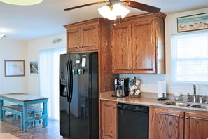 Una cocina con armarios de madera, un refrigerador negro, una cafetera y un lavavajillas.