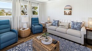 A living room with a sofa, two armchairs, a coffee table, and a wall-mounted lamp. - "Water of Life" offers panoramic views, steps to the beach, screened-in porch, p (Port Saint Joe)