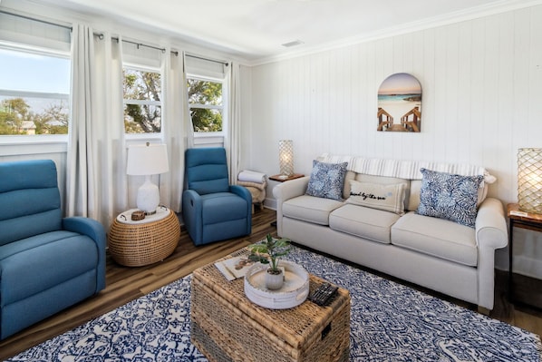 A living room with a sofa, two armchairs, a coffee table, and a wall-mounted lamp. - "Water of Life" offers panoramic views, steps to the beach, screened-in porch, p (Port Saint Joe)