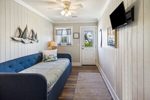 A room with a blue sofa, a ceiling fan, a mounted TV, and a door with a window. - "Water of Life" offers panoramic views, steps to the beach, screened-in porch, p (Port Saint Joe)