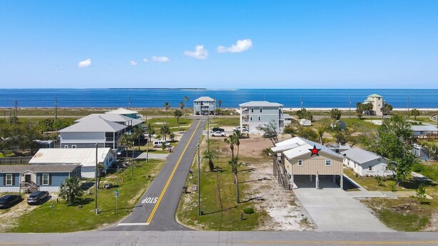 A coastal residential area with a clear road leading to the beach, houses with varying roof styles, and a prominent red star on one building. - "Water of Life" offers panoramic views, steps to the beach, screened-in porch, p (Port Saint Joe)