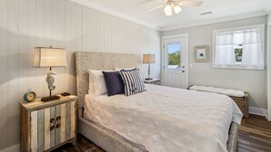 A bedroom with a bed, nightstands, a dresser, a ceiling fan, and a window with curtains. - "Water of Life" offers panoramic views, steps to the beach, screened-in porch, p (Port Saint Joe)