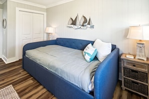 A bedroom with a large bed, a nightstand with a lamp, and a wall decoration of sailboats. - "Water of Life" offers panoramic views, steps to the beach, screened-in porch, p (Port Saint Joe)