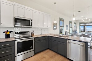 Una cocina moderna con electrodomésticos de acero inoxidable, armarios blancos y encimera de madera.